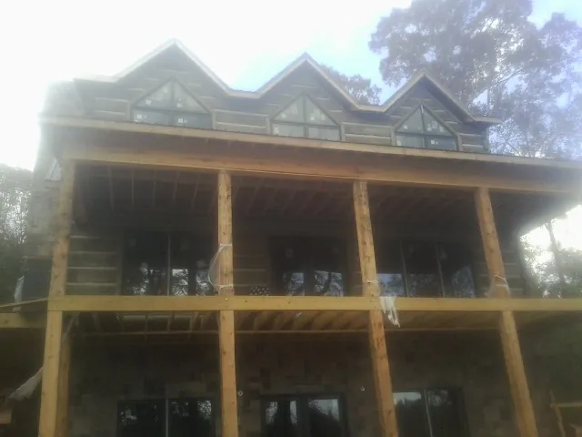 Dormers and porch framing on a large log home under construction — Roof Coating work by our crew in Ocean Isle Beach