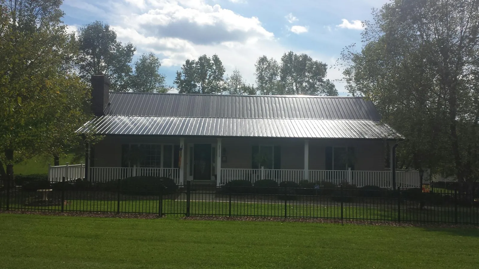 Gray metal roof on a brick ranch with a full width front porch — Gutter Guard Installation work by our crew in Ocean Isle Beach