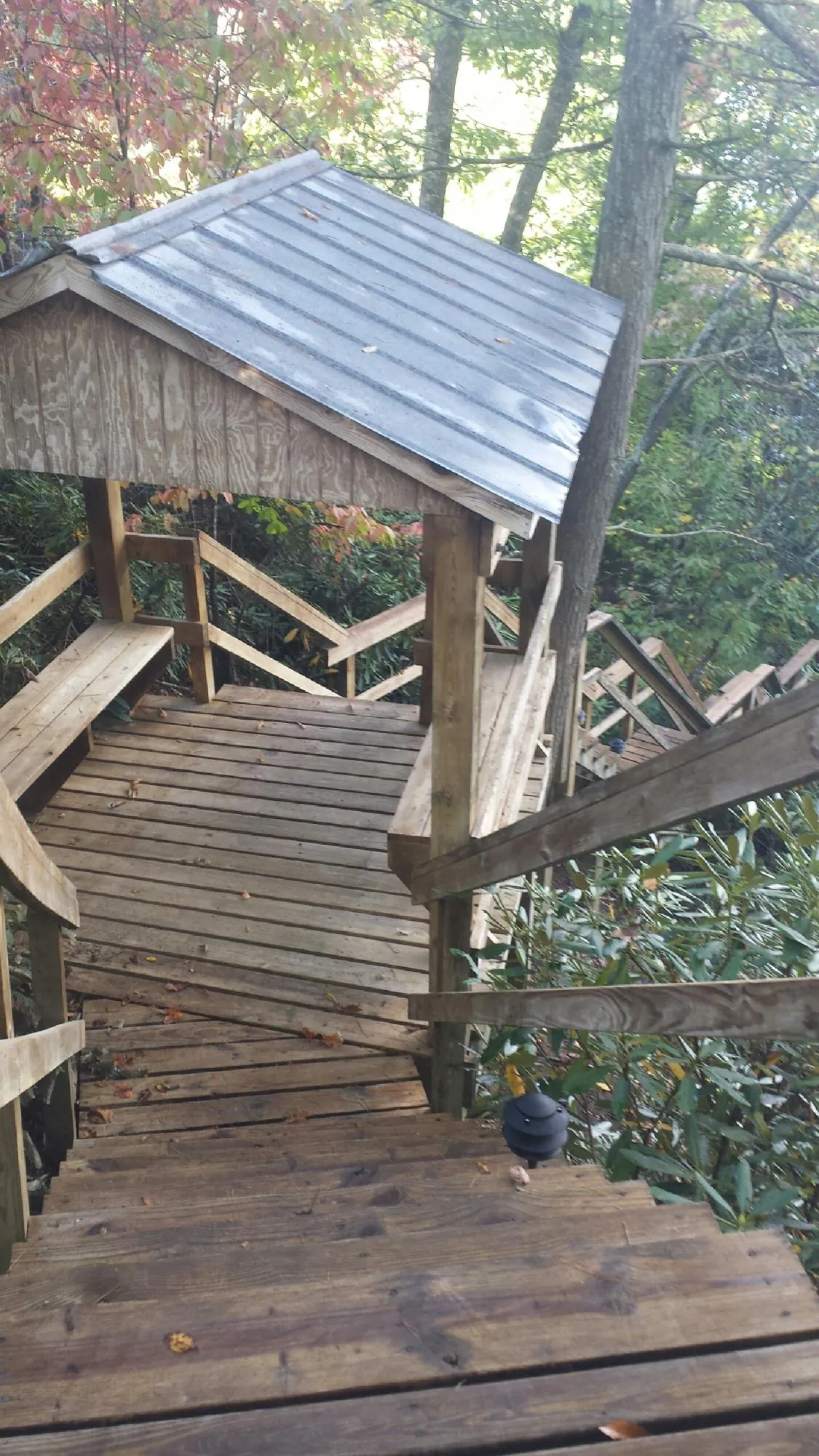 Metal roofed shelter over wooden steps on a wooded walkway — Skylight Repair & Installation work by our crew in Ocean Isle Beach